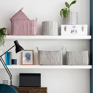 white wall with white shelf laptop lamp and pink and grey bucket