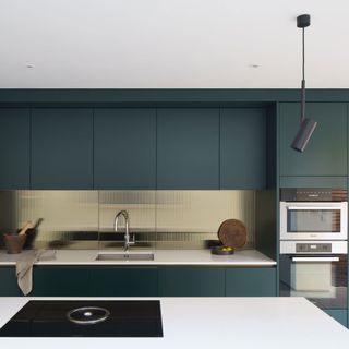 modern green kitchen with kitchen island and a gold splashback