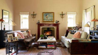 living room with yellow walls and brown velvet sofa and white sofa upholstered footstool and woodburner lit