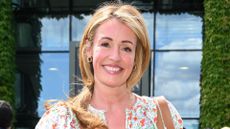 Cat Deeley pictured outside smiling with a floral dress on and her blonde hair tied back