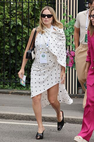 Margot Robbie enters Wimbledon in a high low cape dress with polka dots and an open back