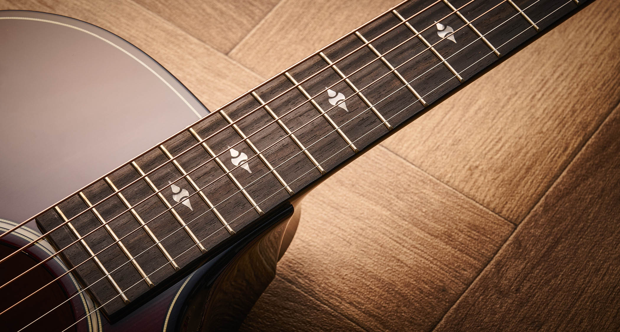 Taylor Builder’s Edition 514ce Kona Burst pictured against a wooden floor and patterned rug.