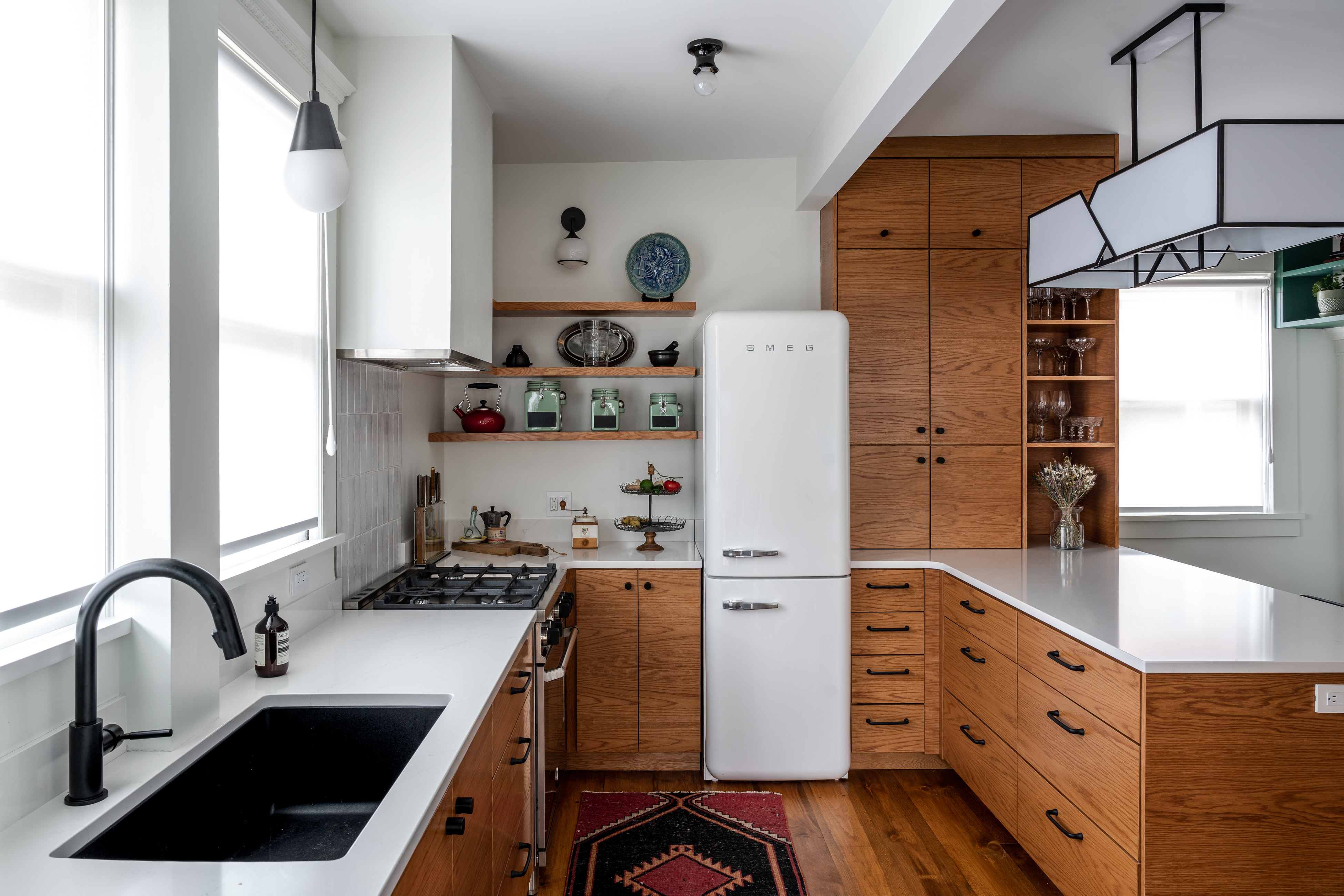 A kitchen in all wood, with a large lighting piece above the peninsula