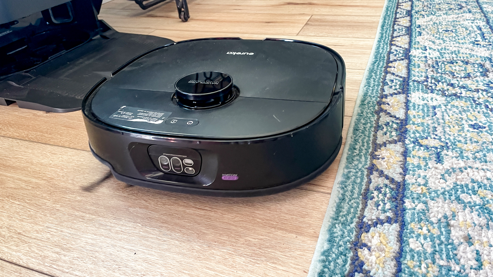 Eureka J15 Max Ultra robot vacuum on hardwood next to rug