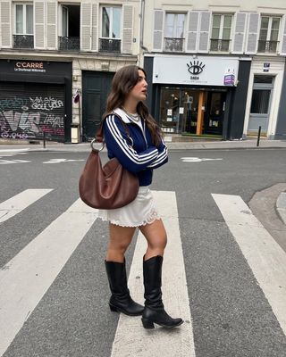 French woman wearing minidress, adidas jacket, and tall black boots