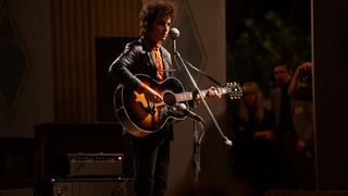 Timothée Chalamet as Bob Dylan, playing an SJ-200 onstage in a still from the forthcoming biopic A Complete Unknown