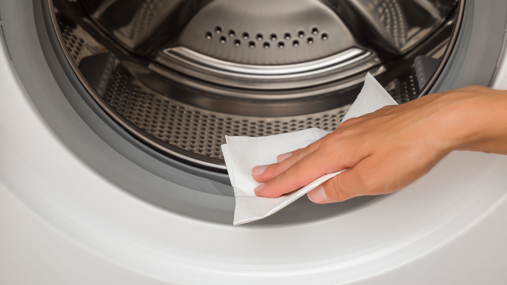 picture of woman wiping washing machine seal with kitchen paper