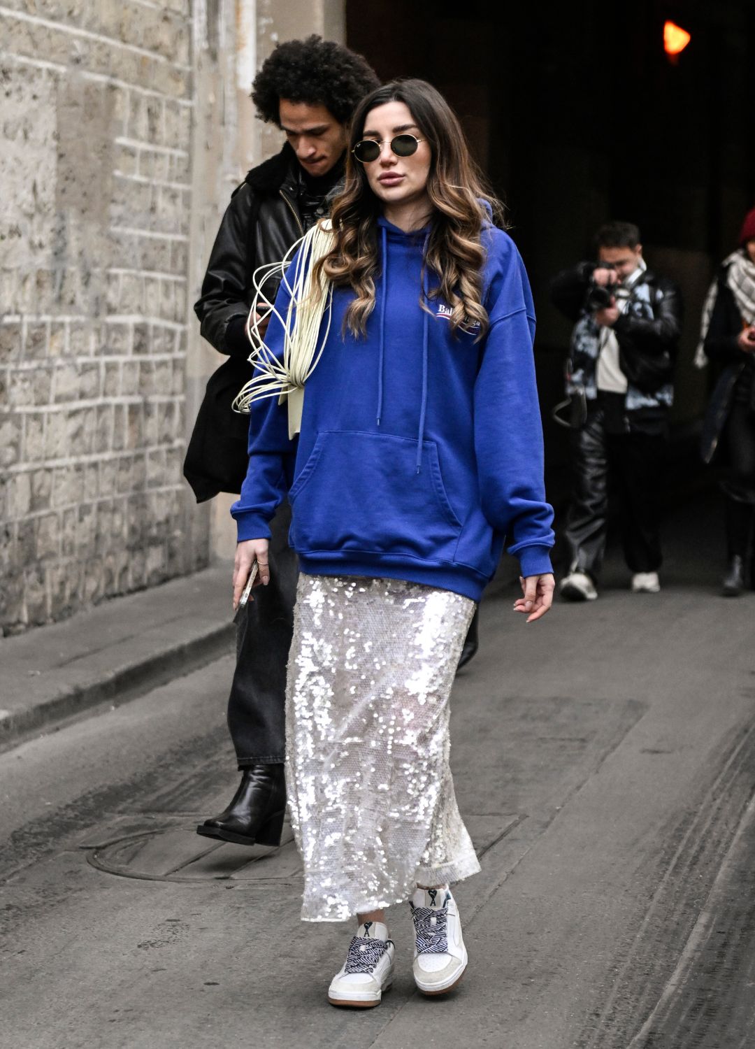 A guest is seen wearing a blue hoodie, sequin skirt and cream sneakers outside the Rokh show during Paris Fashion Week F/W 2023 on March 06, 2023 in Paris, France