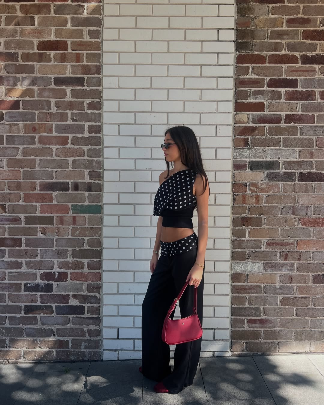 Influencer Ebony Aroha in a two-piece polka-dot set red bag and '90s square glasses.