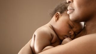 A Black woman holds a baby close to her chest