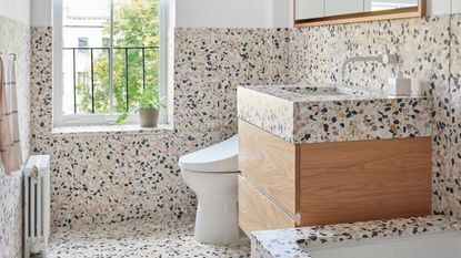 terrazzo bathroom with floating timber vanity, white toilet, radiator, built-in bath