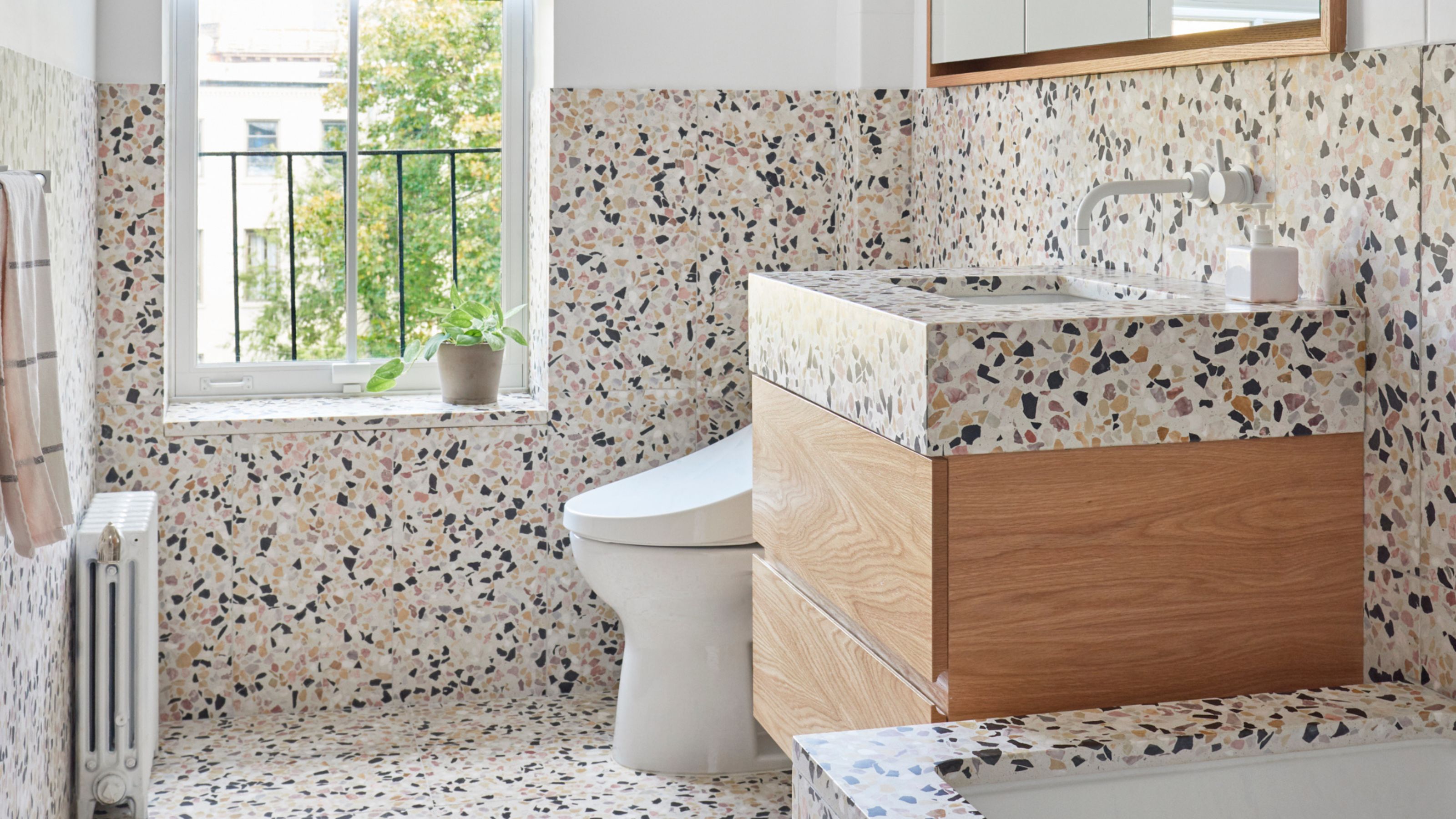 terrazzo bathroom with floating timber vanity, white toilet, radiator, built-in bath