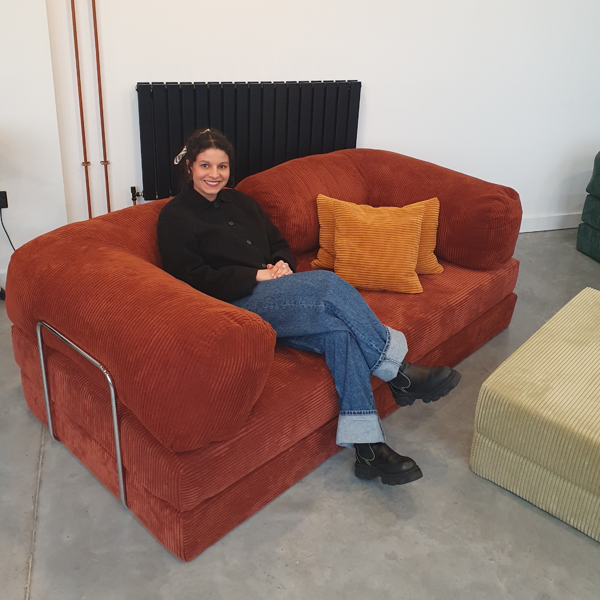 Sara sitting on the Teddy sofa by OMHU in Rust at the brand's London showroom