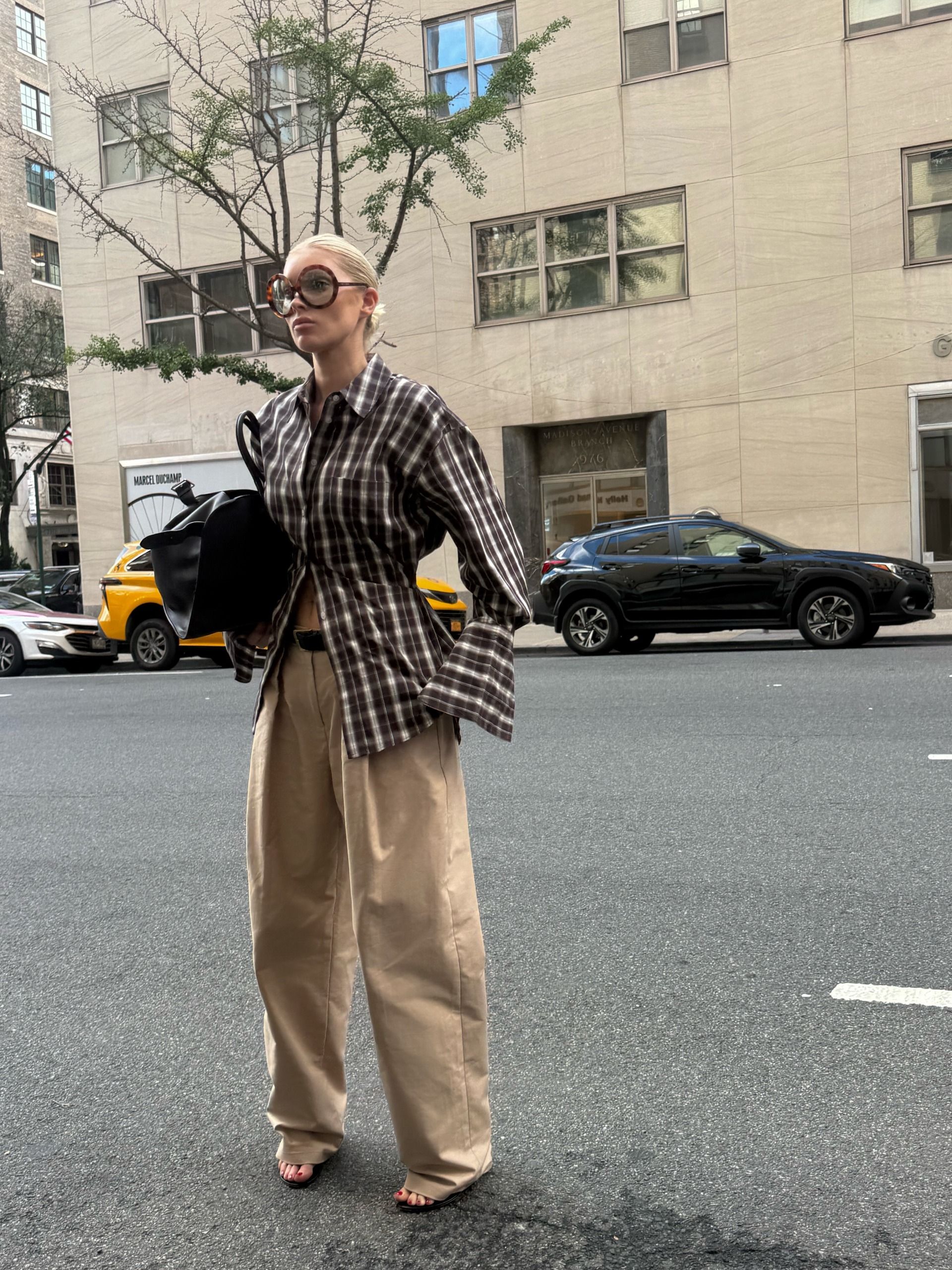 An image of Elsa Hosk wearing beige trousers with a checked shirt whilst in New York.