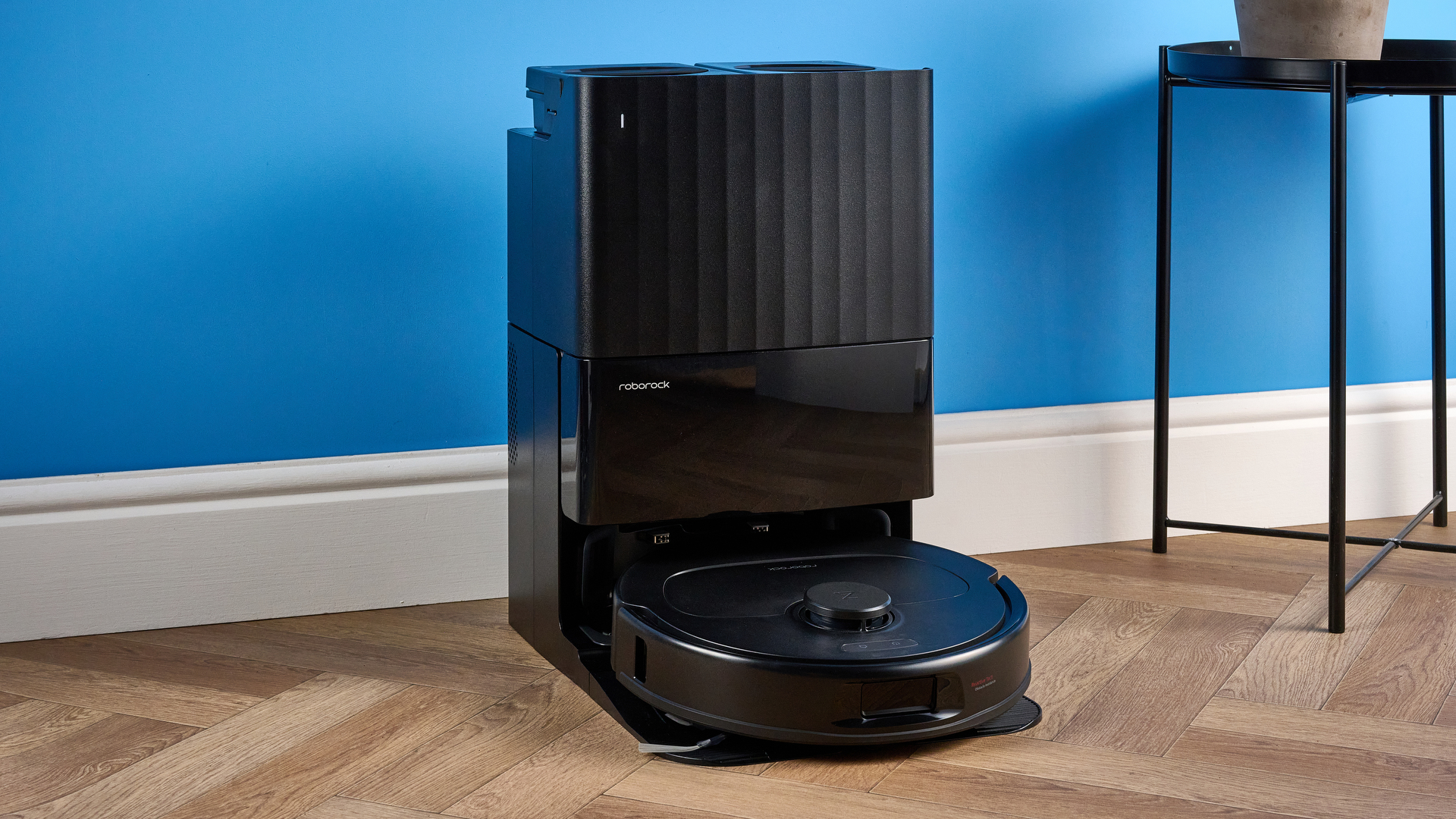 Roborock QV 35S with dock photographed in front of a blue background