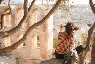 Rear View Of Woman Sitting On Branch At Acropolis Of Athens