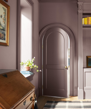 purple room with arched door, window ledge and vintage wooden dresser