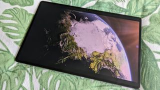 Samsung Galaxy Tab S9 Ultra 5G on leafy bedsheets displaying picture of the world