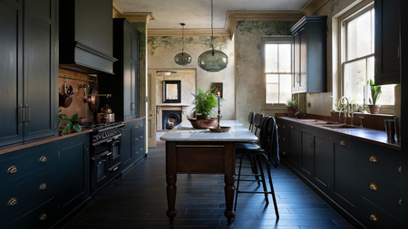 A large kitchen with a small marble top island and lighting overhead