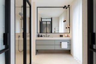 An example of how to make a small bathroom look bigger showing a bathroom with a large mirror over a vanity