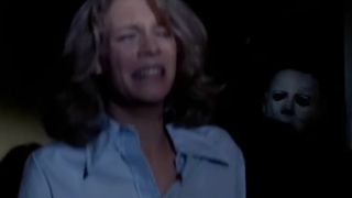 Laurie Strode cries in her room with Michael Myers stalking her from behind