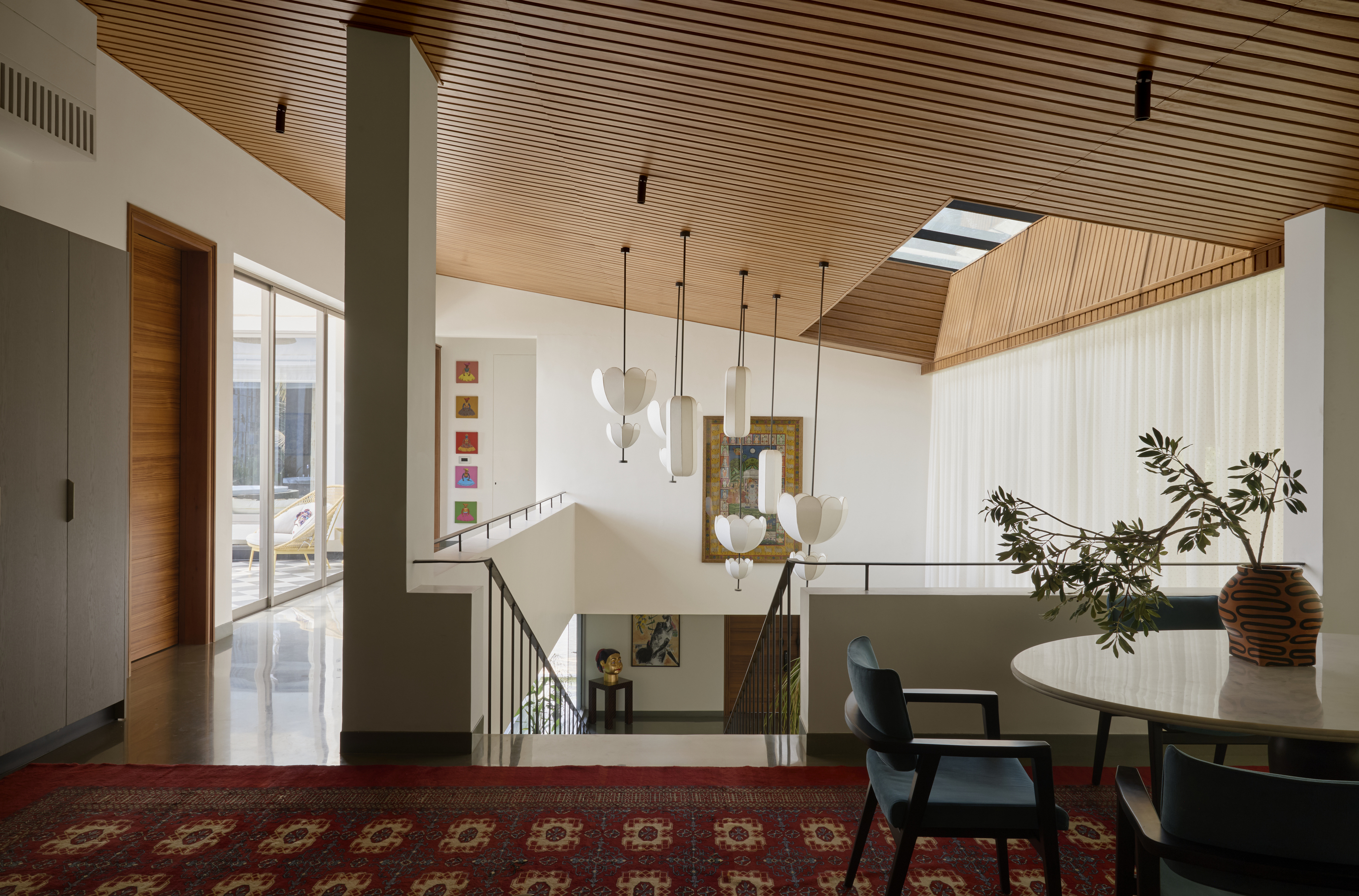 An upstairs area with a small library-style seating, chairs, a table and ceiling lights