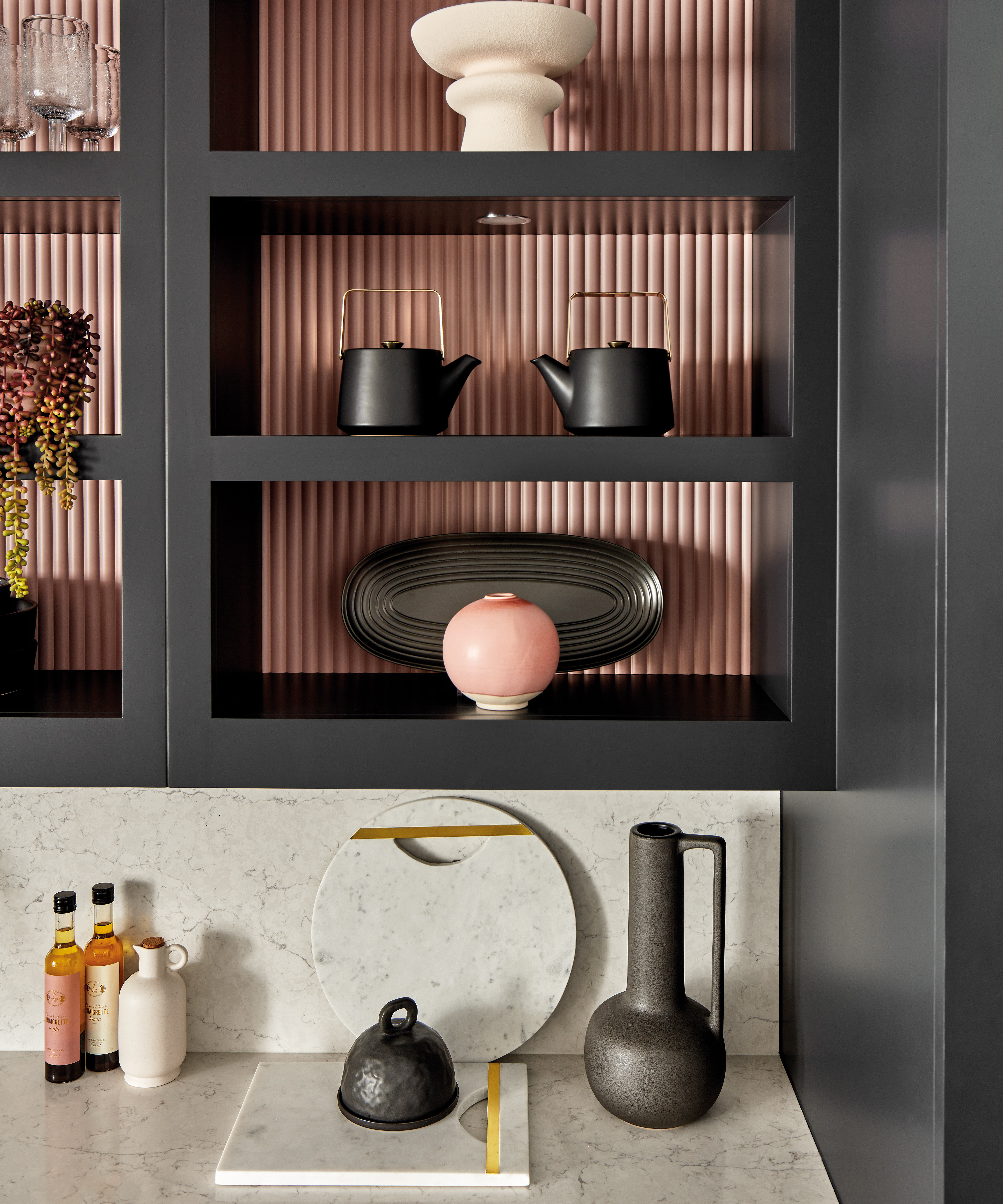 black open shelving in kitchen with pink fluted back panels and light coloured worktop below