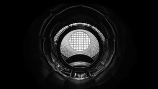 Low-key image, showing an up looking perspective from an inside of a historic building, where window features and stair railing were turned into abstract shapes and form