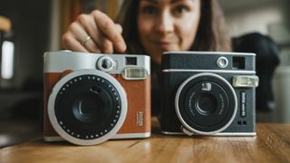 Two instax cameras on a wooden bench