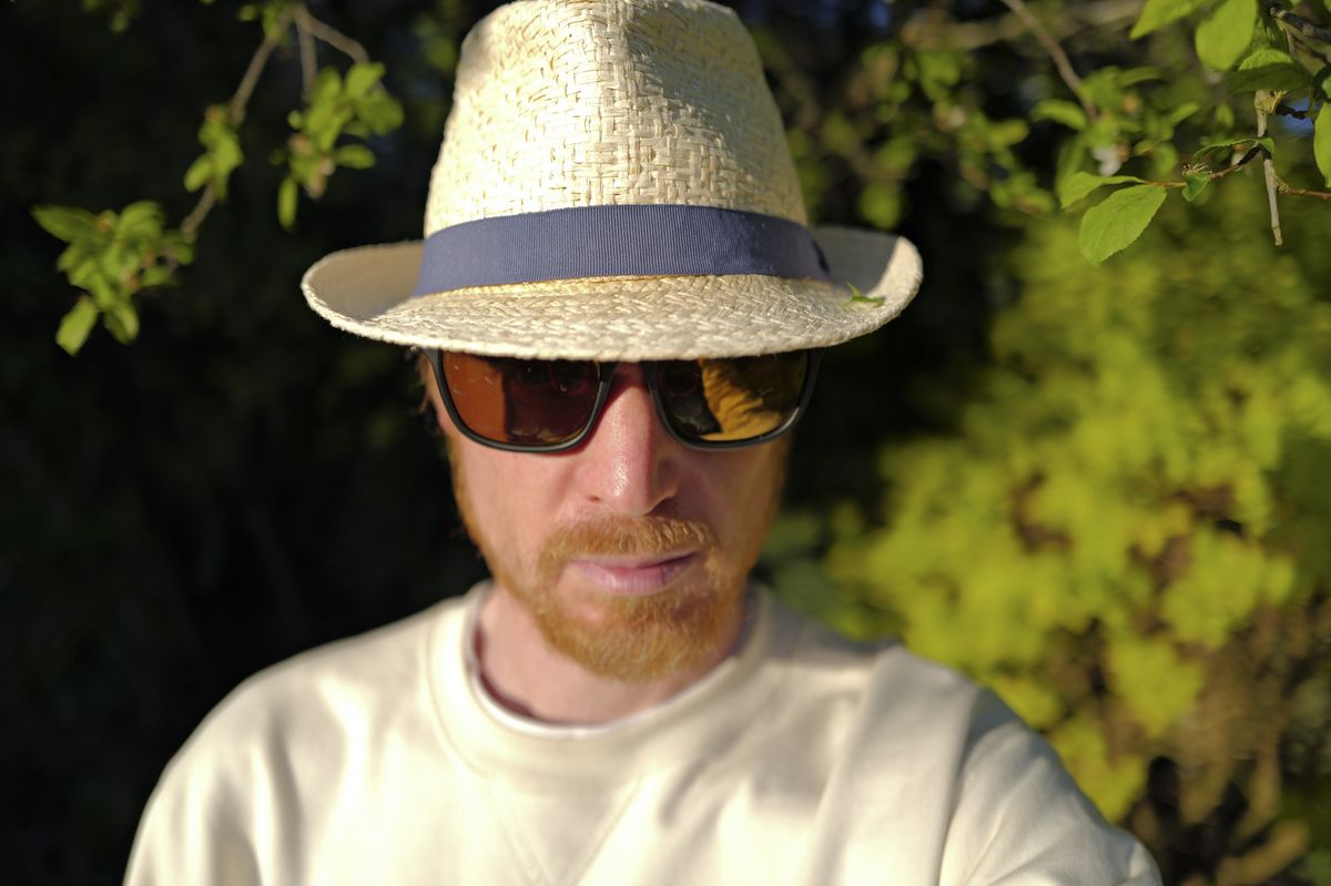 Leica Q3 sample photos &ndash; portrait of a man in a trilby and shades, lit by setting sun