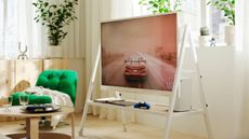 living room with white rolling tv stand, a timber console with candle holder and potter plant, and round coffee table with green armchair