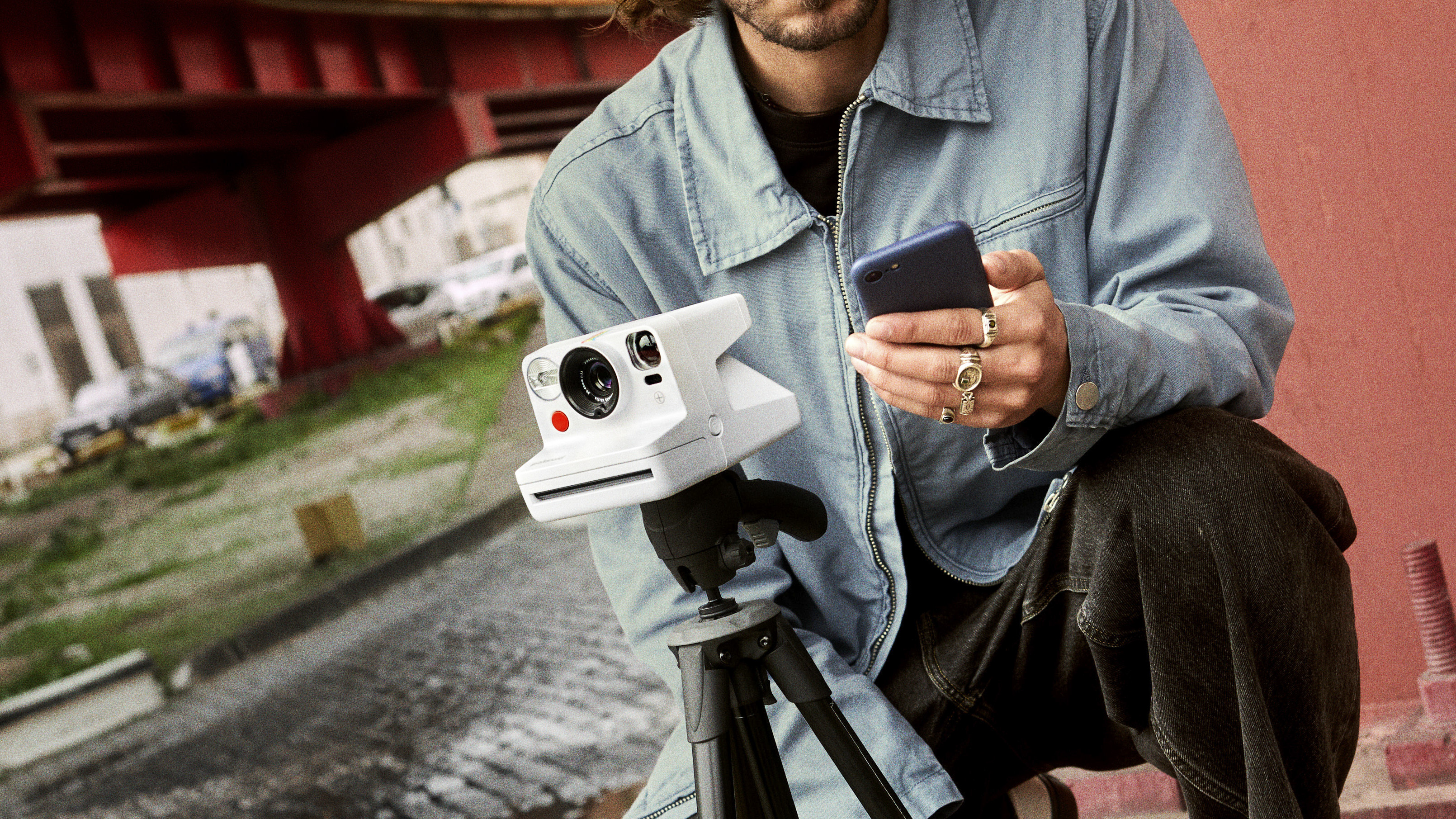 Polaroid Now 3+ instant camera on tripod with user controlling it with a phone