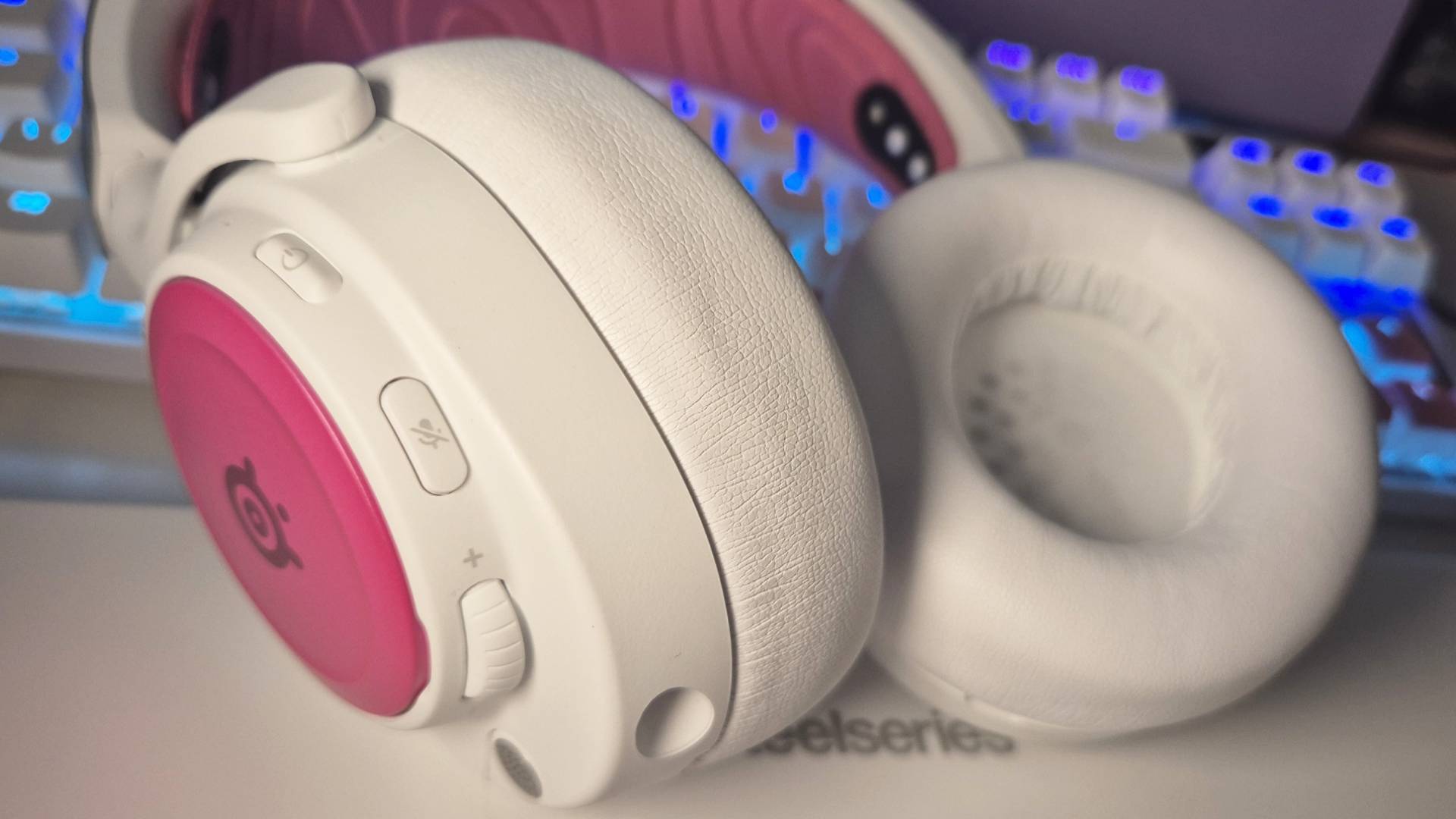 Фотография беспроводной игровой гарнитуры SteelSeries Arctis Nova Pro белого цвета, сделанная Розали Ньюкомб, с аксессуарами SteelSeries розового цвета в комплекте.