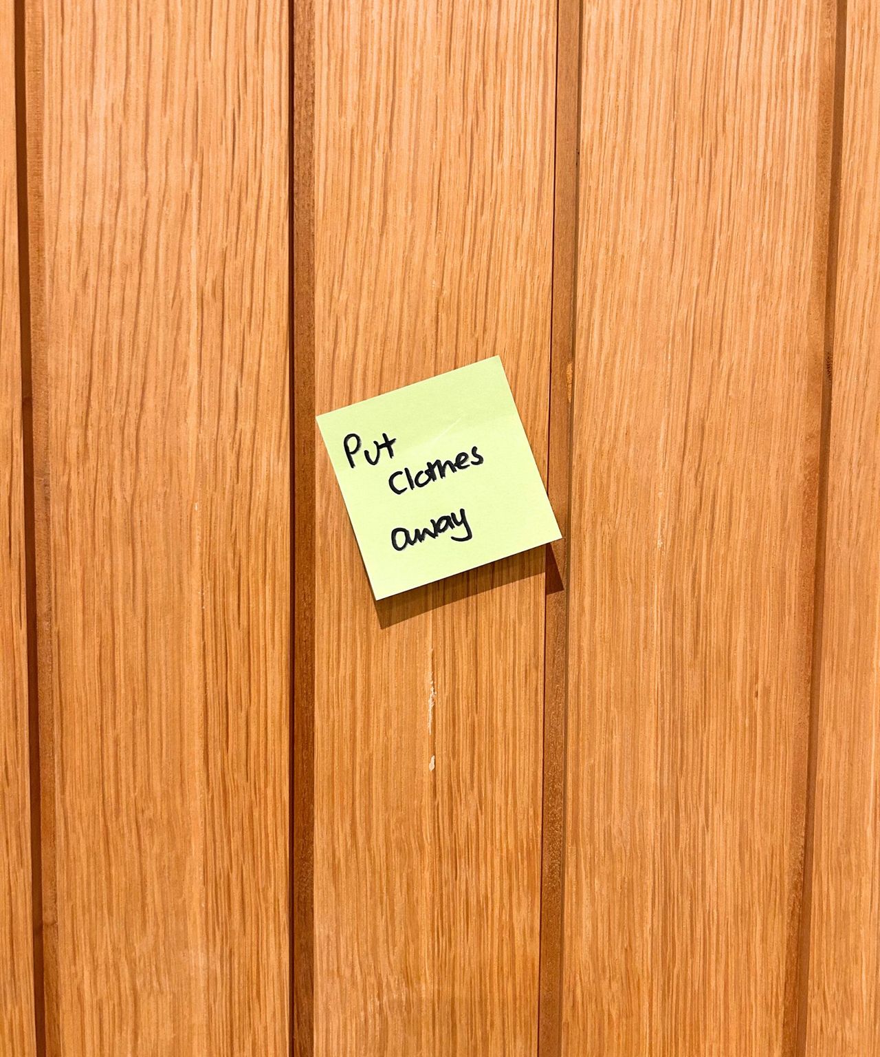 Wooden door with bright green Post-it note on it