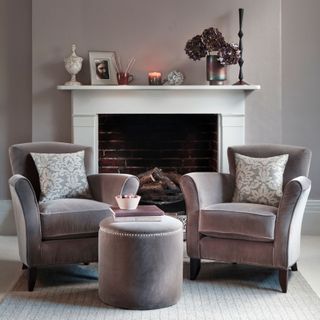 Grey living room with two grey armchairs in front of a white fireplace