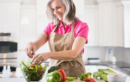 A middle-aged woman preparing a salad as part of a menopause diet