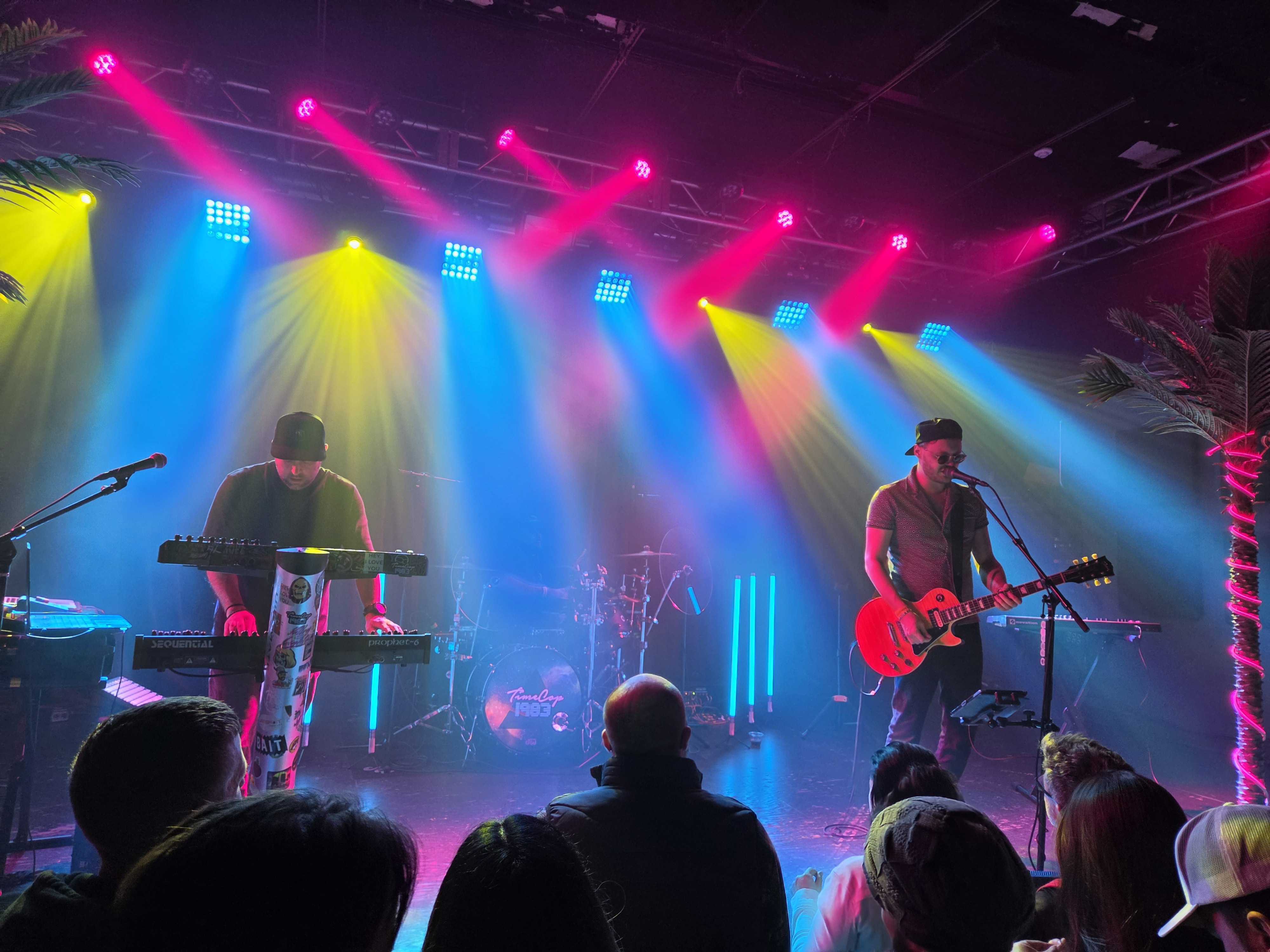 Two men playing instruments with colorful lights above