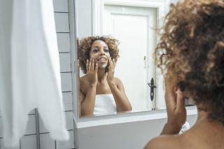 Woman applying face cream in the bathroom