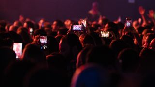 Best budget phones for music: A crowd of people holding up their phones during a gig