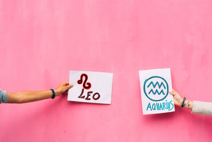 woman&#039;s arms holding signs with leo and aquariums, zodiac signs