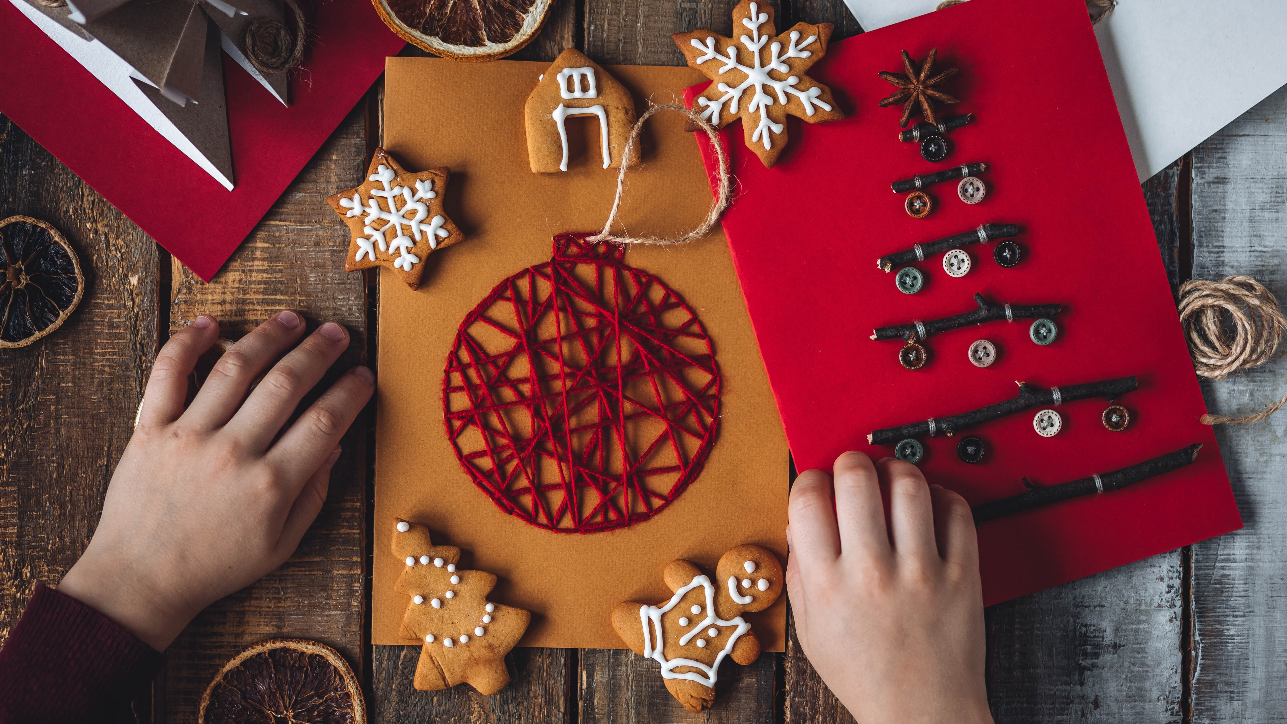 طفل يصنع بطاقات عيد الميلاد باستخدام الأزرار والخيط الأحمر والعصي