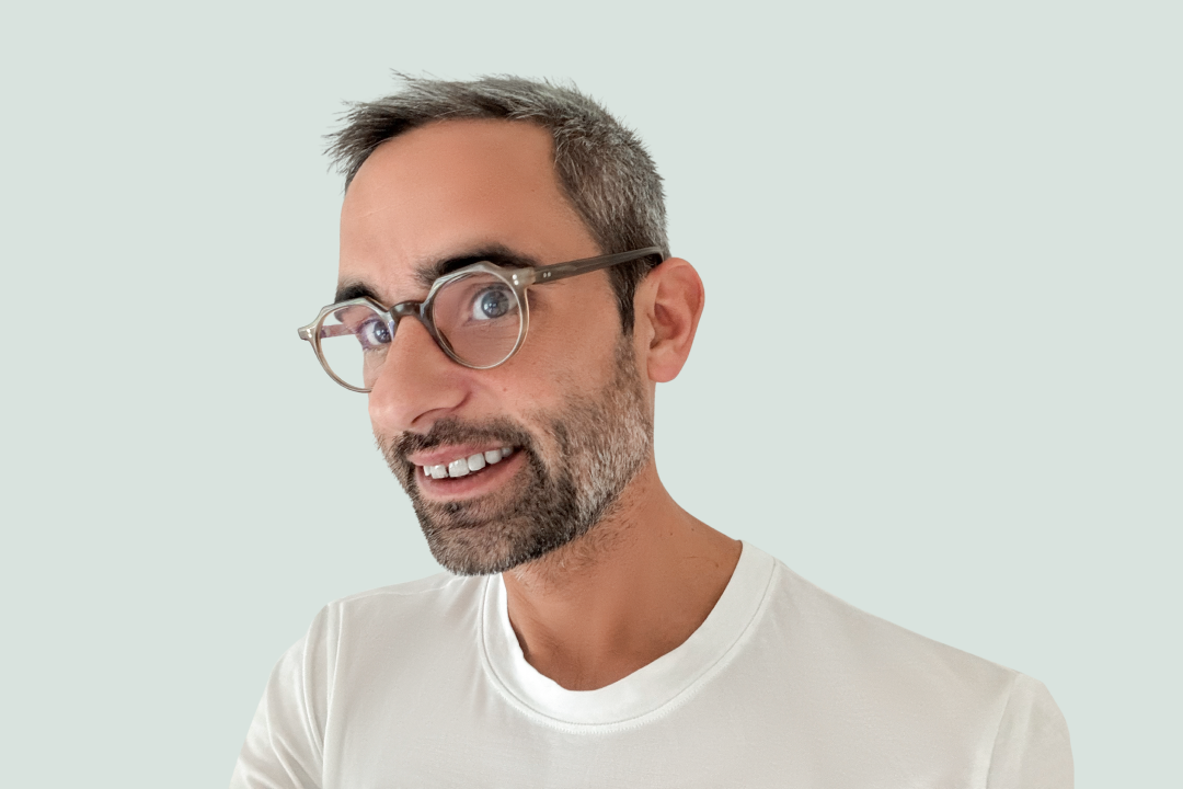 man with glasses wearing a white t-shirt on a light background