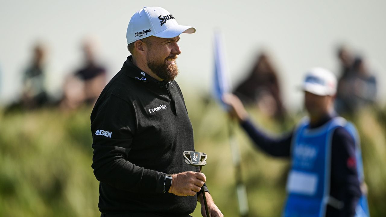 Shane Lowry hands his putter to his caddie