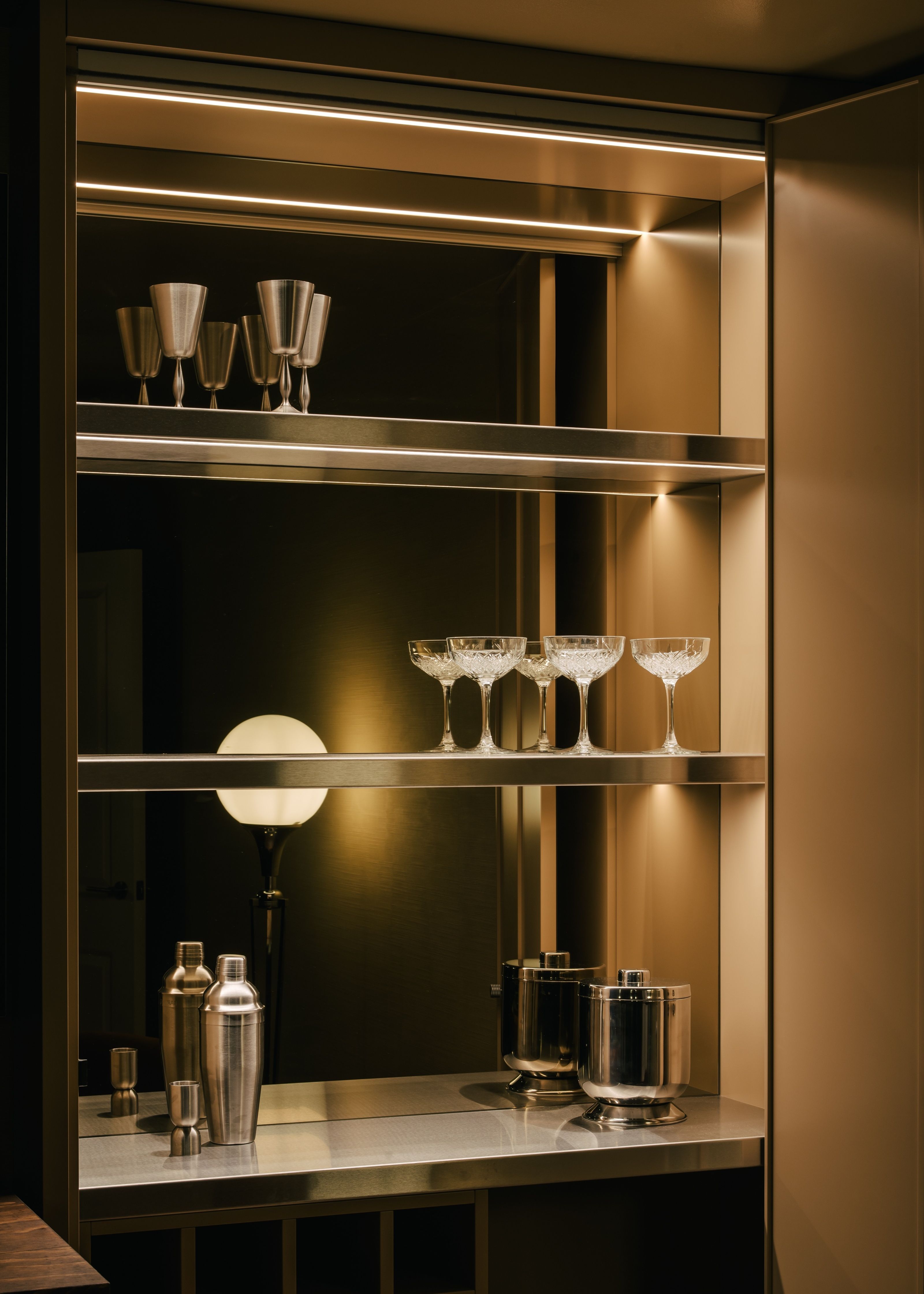 a home bar with glamorous mirrored shelves and cocktail accessories