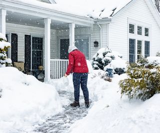 A woman de-icing a path