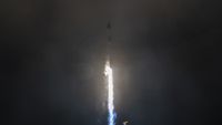 A white rocket blasts off in the dark of night.