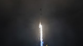 A white rocket blasts off in the dark of night.