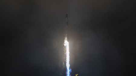 A white rocket blasts off in the dark of night.