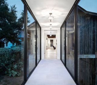 Glass link bridge with steel framed windows and views of garden outside