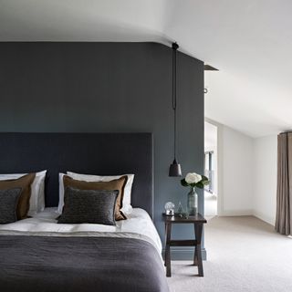 Dark grey wall, white wall and grey carpet, white and grey bed with wooden bedside table